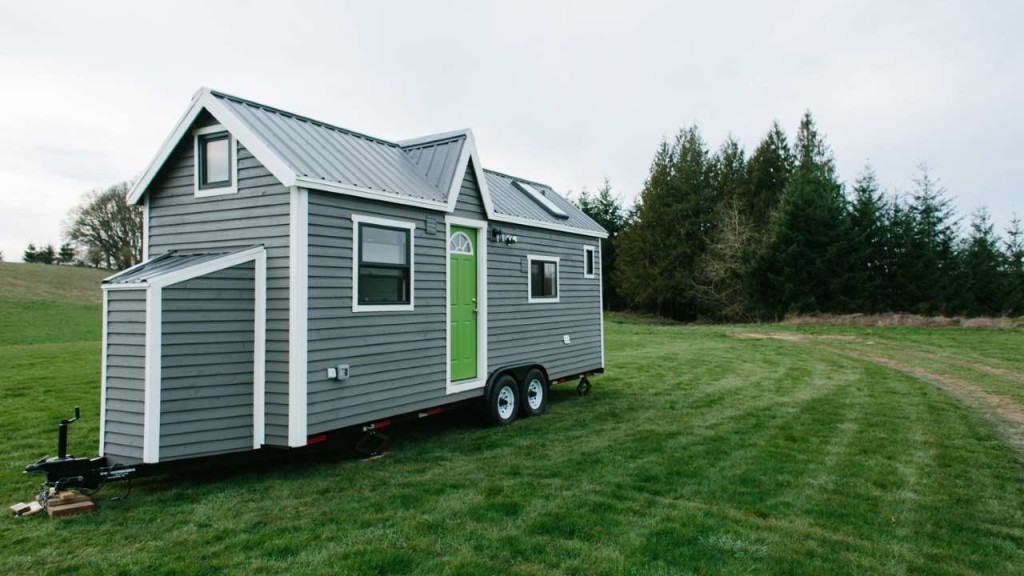 tiny house by tiny heirloom a small grey house in a field with green trees in the background