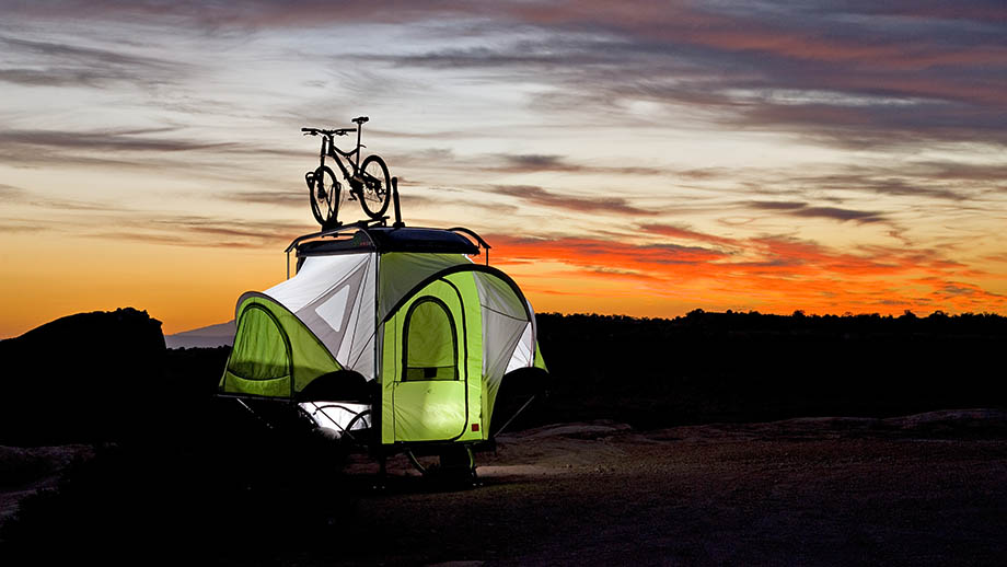 adventure trailers by sylvan sport featuring a green pop up camper in the woods during a sunset