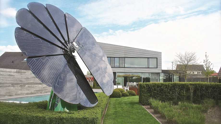 solar energy by Smartflower on a lawn with a luxury house in the background