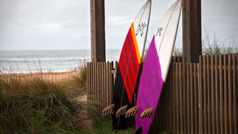 surfboards by Maria Riding Company two surfboards leaning on a fence at the ocean