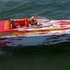 Spectre 36 powerboat speeding across open water with passengers enjoying the ride, powered by twin Mercury outboard engines.