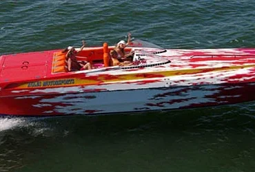 Spectre 36 powerboat speeding across open water with passengers enjoying the ride, powered by twin Mercury outboard engines.